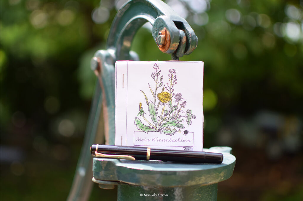 Ein selbstgemachtes "Wiesenbüchlein" aus der Grundschule und ein Füller steht als Symbol für Whitepaper, die Texterin Manuela Krämer schreibt.