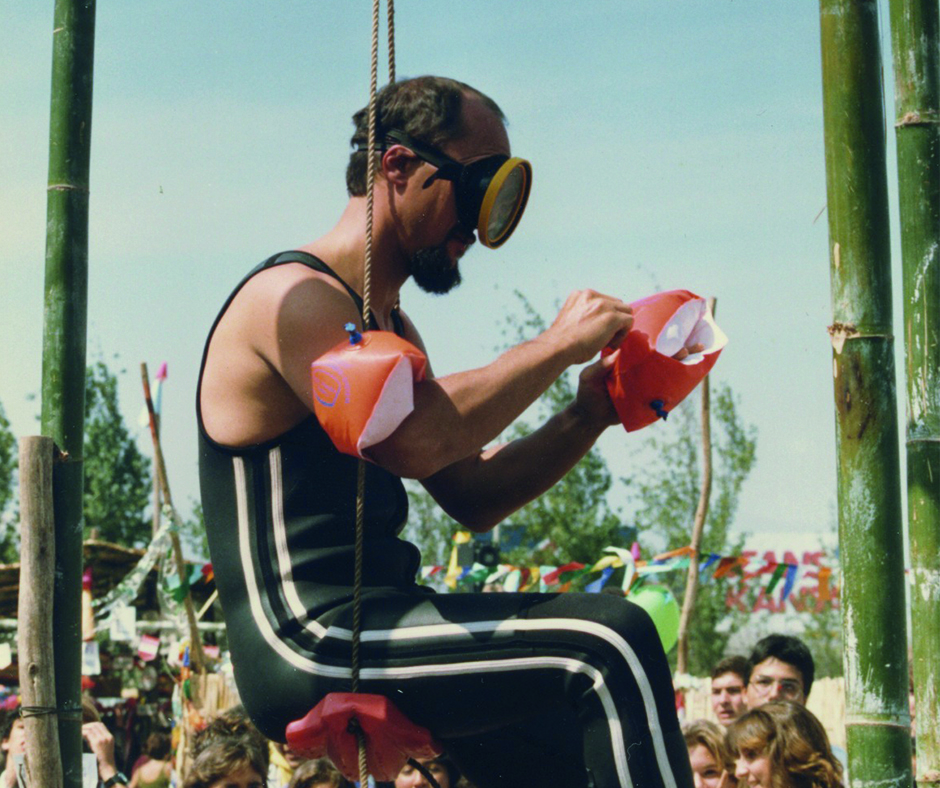 Mann im Taucheranzug und Schwimmflügeln auf Schaukel