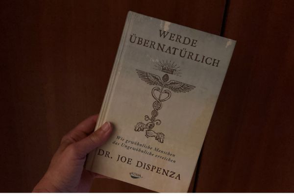 Hand hält Buch von Joe Dispenza hoch.